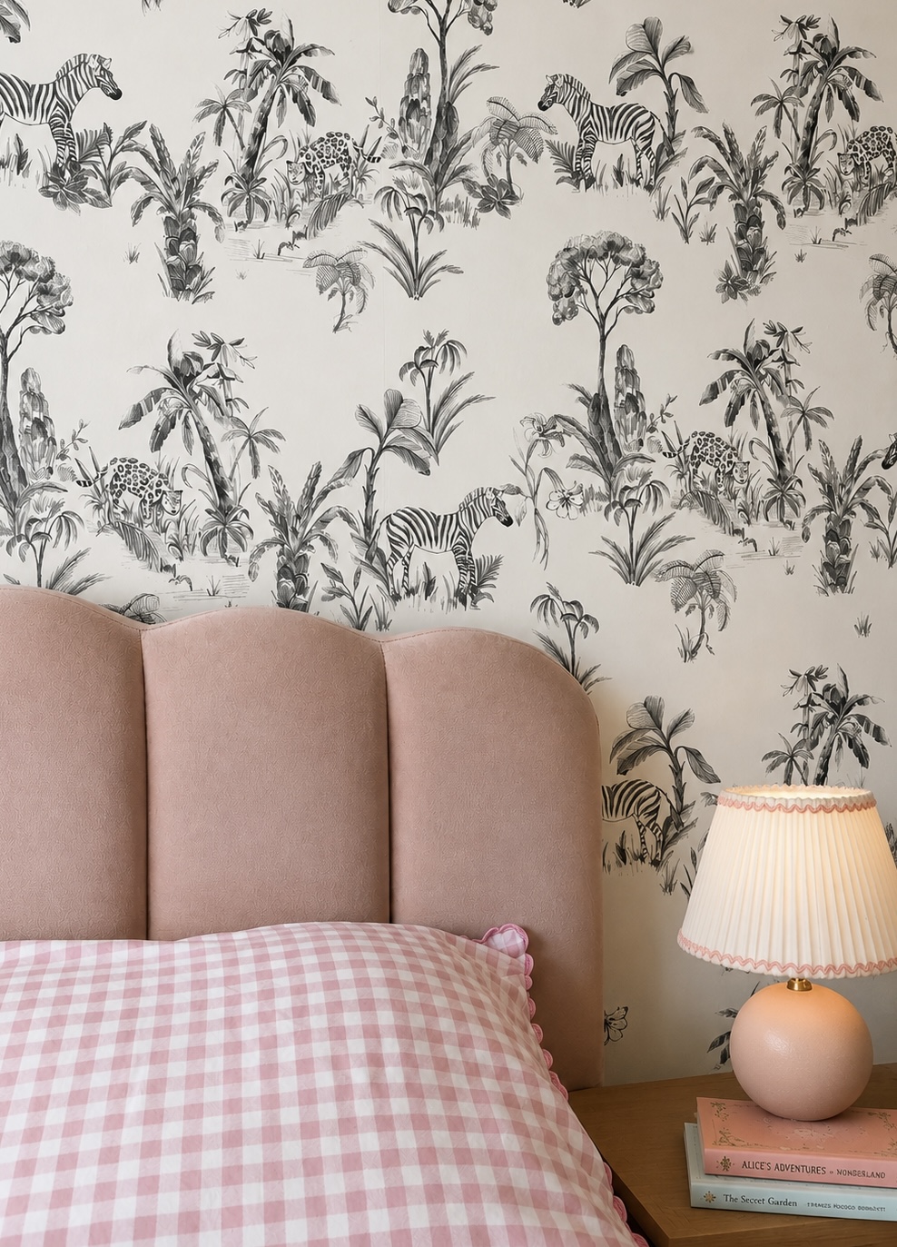Child's bedroom with pink scalloped headboard and monochrome jungle wallpaper
