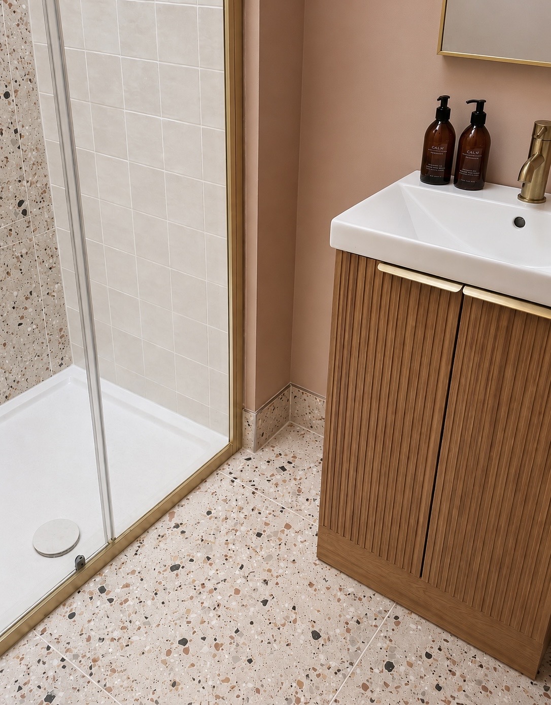 Bathroom with fluted wood vanity, brass tap and terrazzo floor